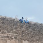 יהודי טיפס על אבני הכותל במהלך תפילת הנץ ותלה שלטים צילום: הקרן למורשת הכותל המערבי